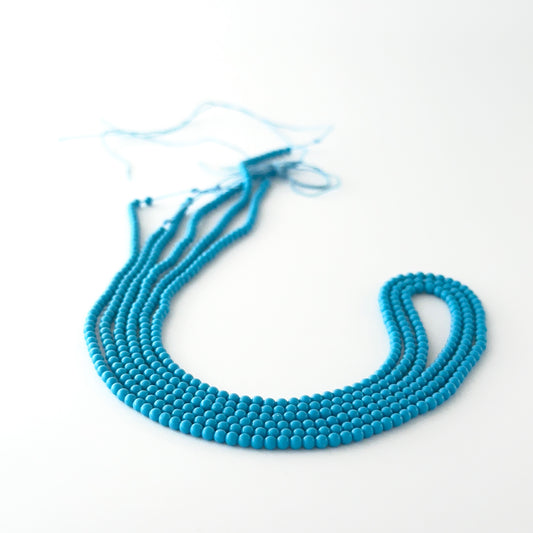 Smooth round Howlite Turquoise beads arranged neatly, highlighting their glossy surface and handmade jewellery component quality