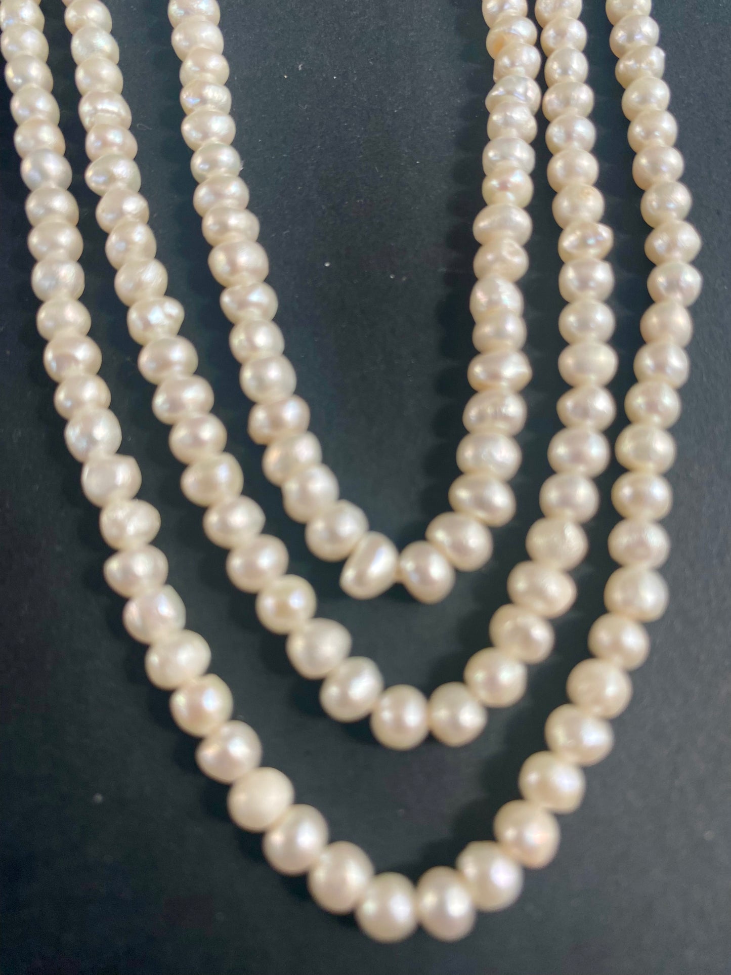 Delicate strands of 5.5-6mm freshwater rice pearls elegantly displayed on a smooth black surface.