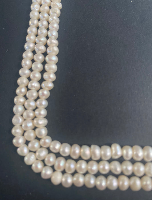Multiple beautiful strands of 5.5mm-6mm freshwater rice pearls resting on a sleek black background, showcasing their lustre.