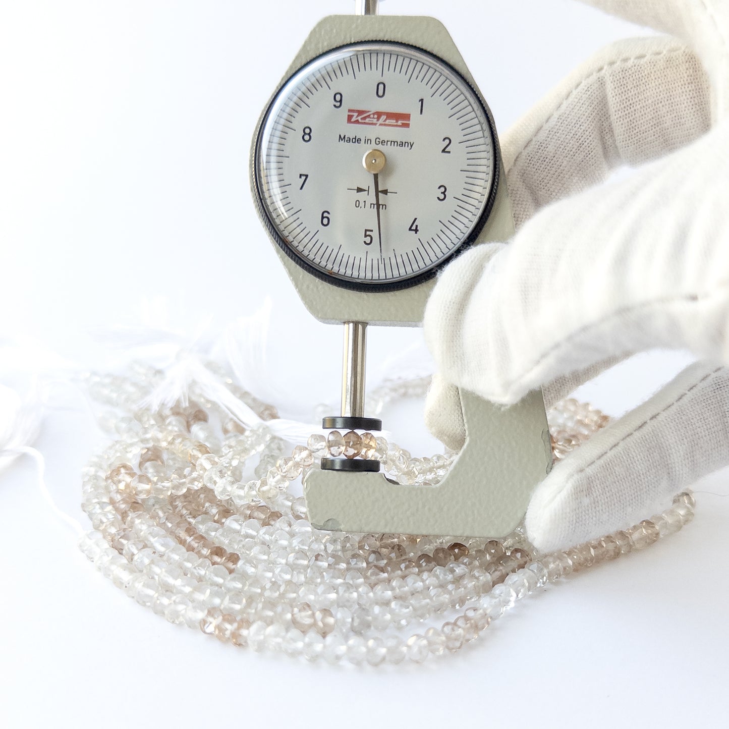 A dial gauge measures the Imperial White Topaz faceted rondelle 4.5mm gemstone.
