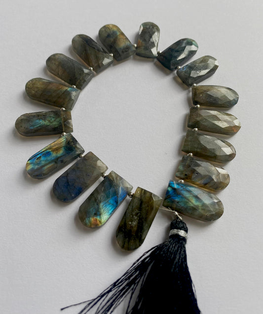 Close-up of labradorite gemstone beads showing their faceted pentagon cut and natural iridescence.
