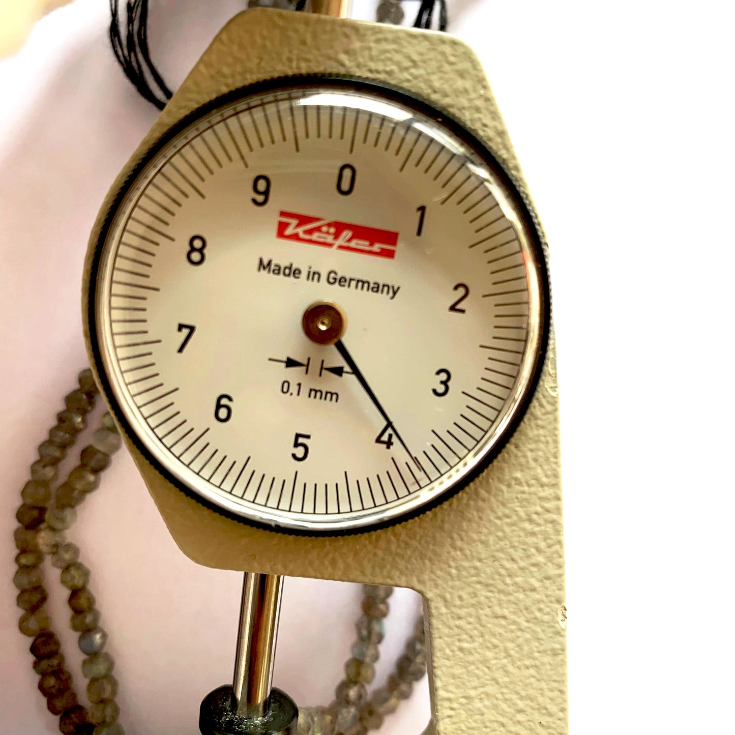 A dial gauge measures the Labradorite faceted rondelle 4.0mm gemstone.
