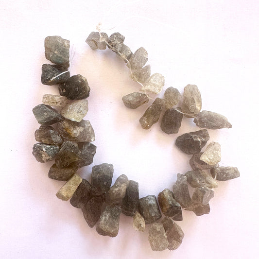 Close-up of raw labradorite gemstones arranged in a 40-piece strand with natural shimmer.
