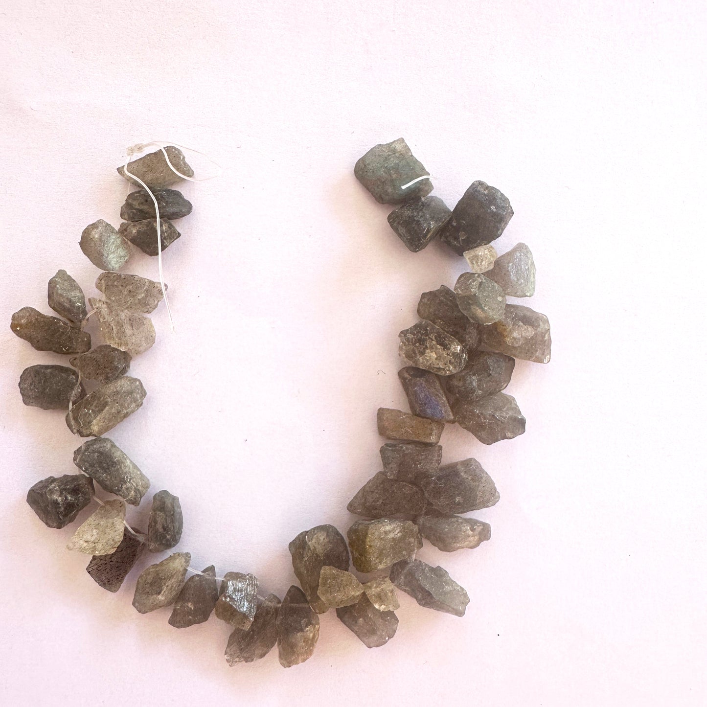 Uncut labradorite beads showing blue-green fire and organic texture.