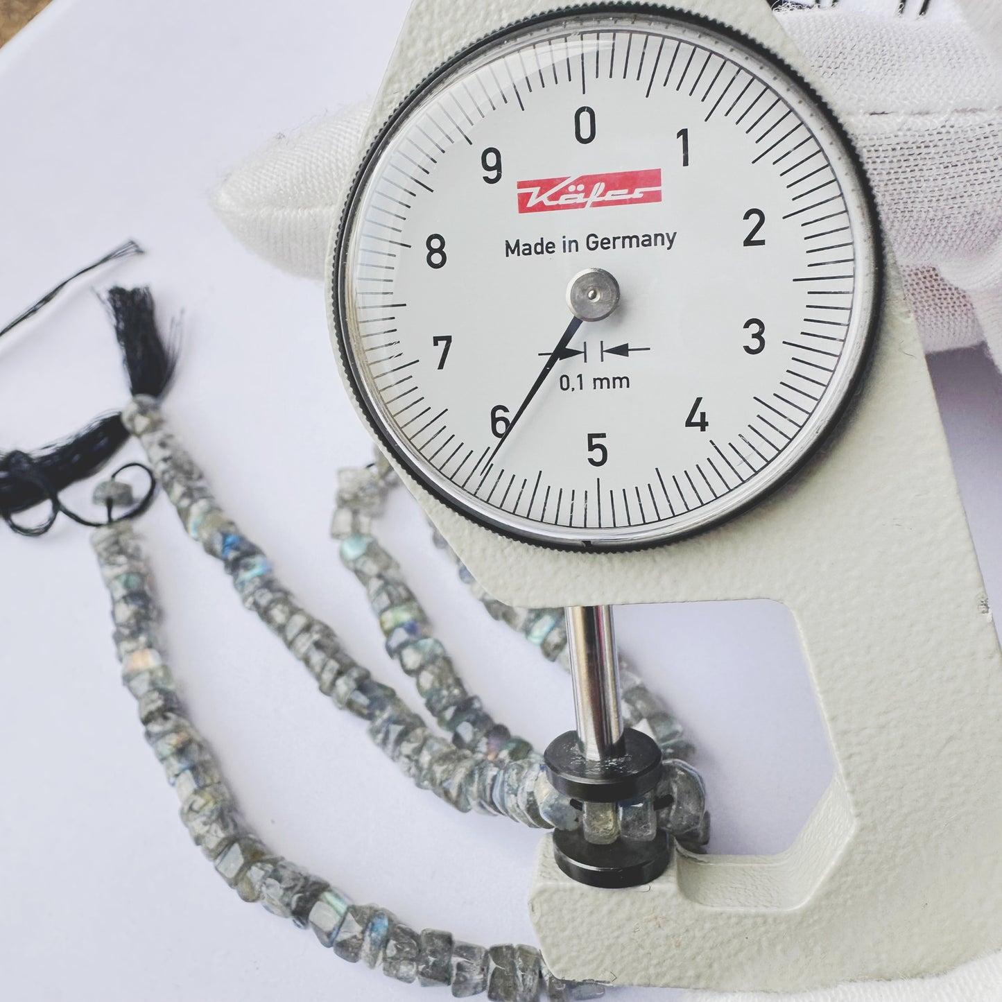 A dial gauge measures the Labradorite smooth wheel 5.5mm gemstone.