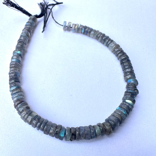 Close-up of natural gemstone beads showing smooth wheel cut and subtle iridescent glow.