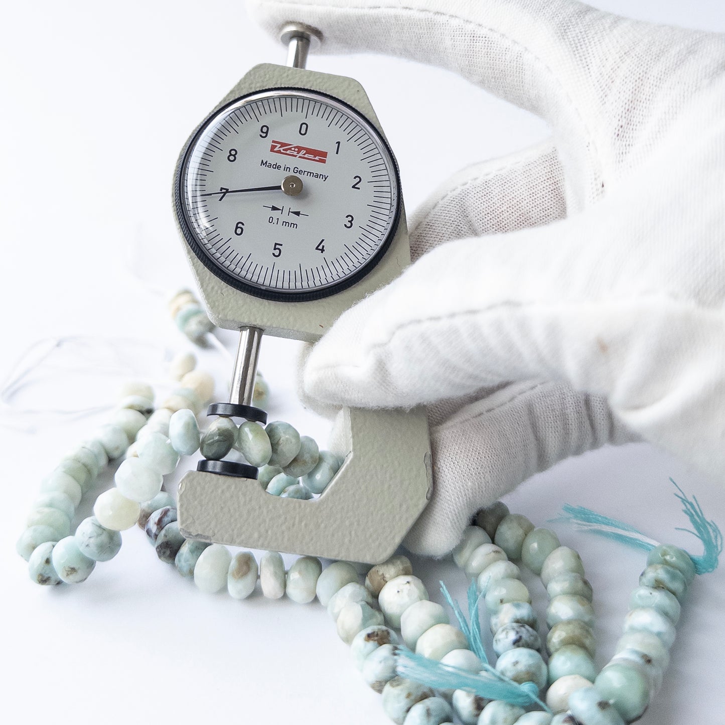 A dial gauge measures the Larimar faceted rondelle 7.3–8mm gemstone.