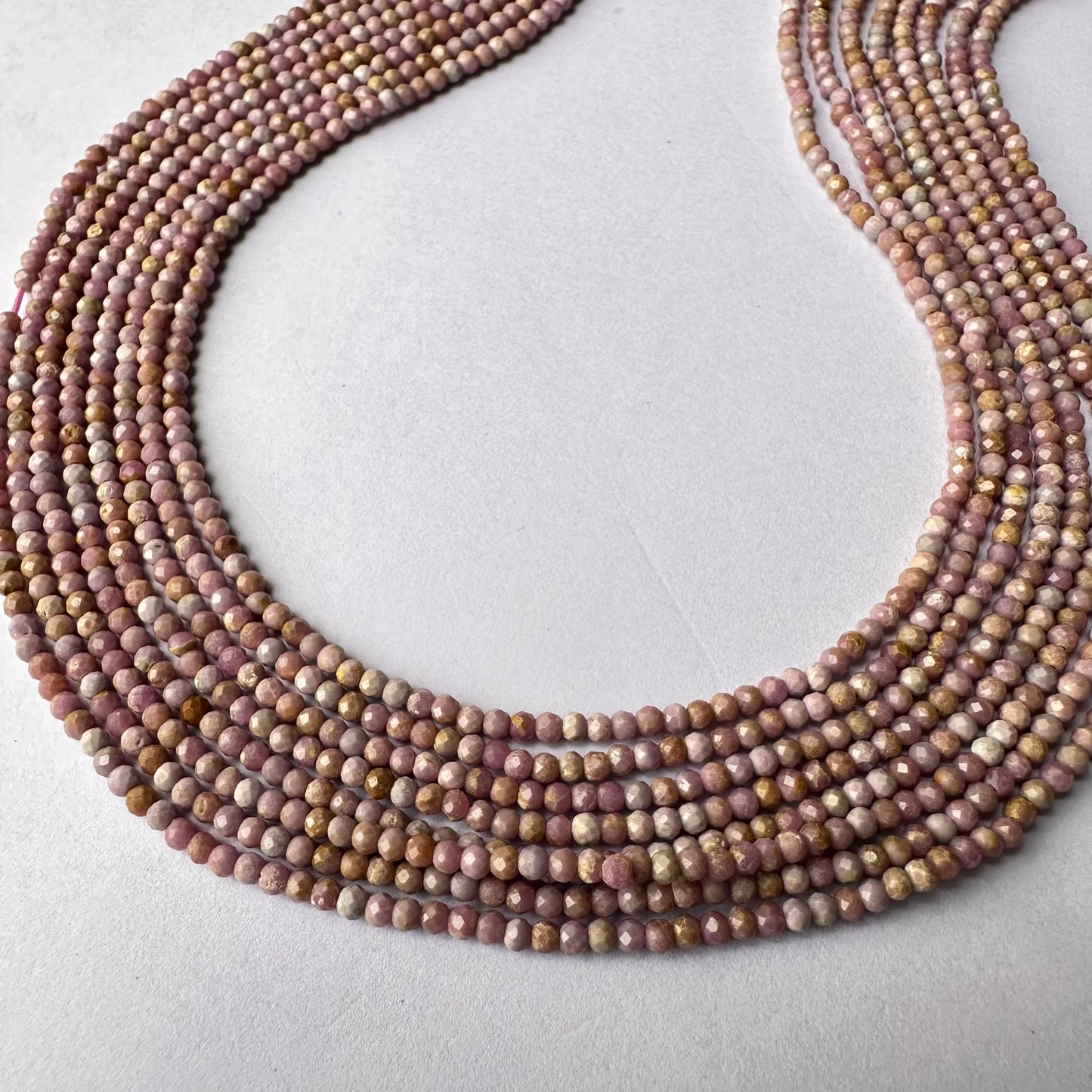 Close-up of Lavender Opal beads showing faceted cut and soft pink hues.