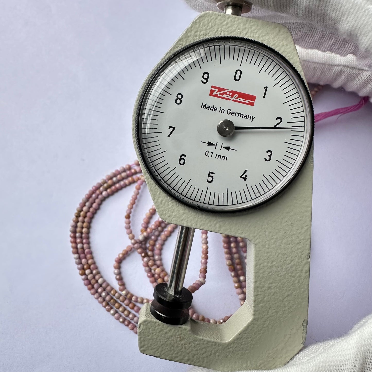 A dial gauge measures the Lavender Opal faceted rondelle 2.2mm gemstone.