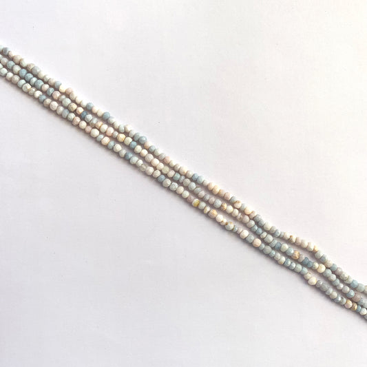 Close-up of 3.5-4mm lavender opal beads with faceted shine and translucent pastel colouring.