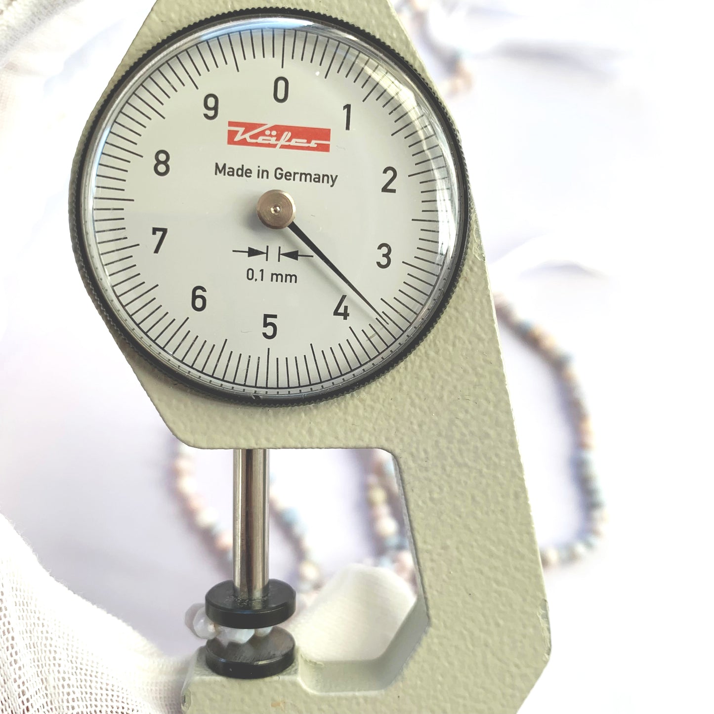 A dial gauge measures the Lavender Opal faceted rondelle 3.5-4mm gemstone.