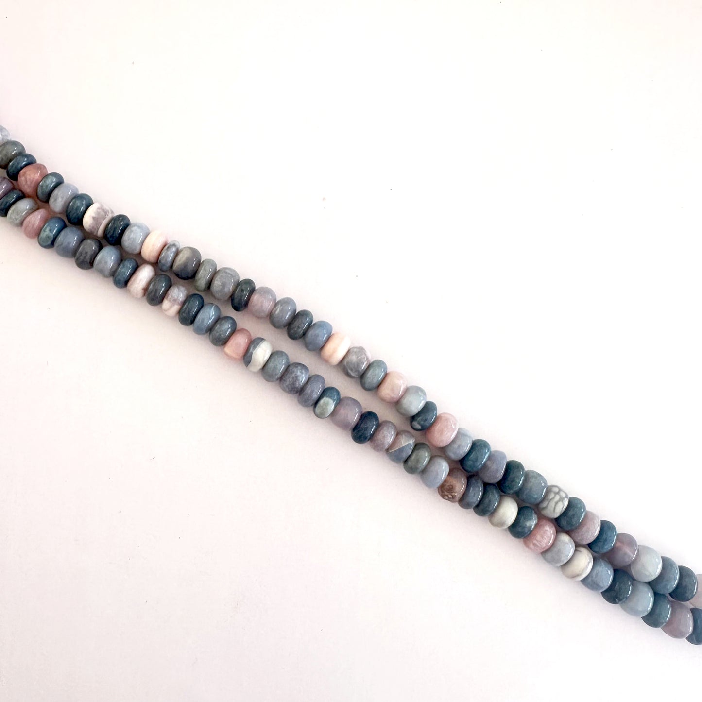 Lavender Opal beads laid out in rondelle formation showing natural variation and shine.