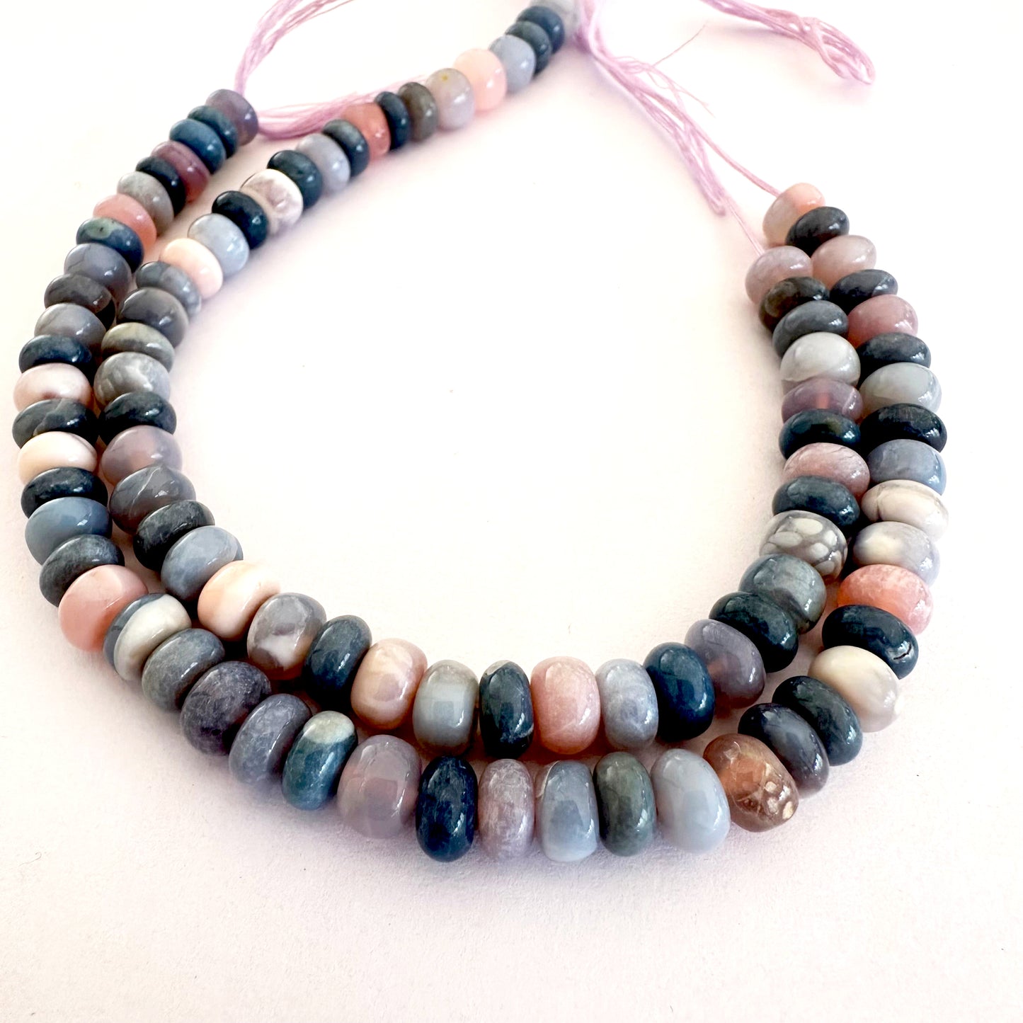 Close-up of smooth Lavender Opal gemstones arranged on a 20cm strand