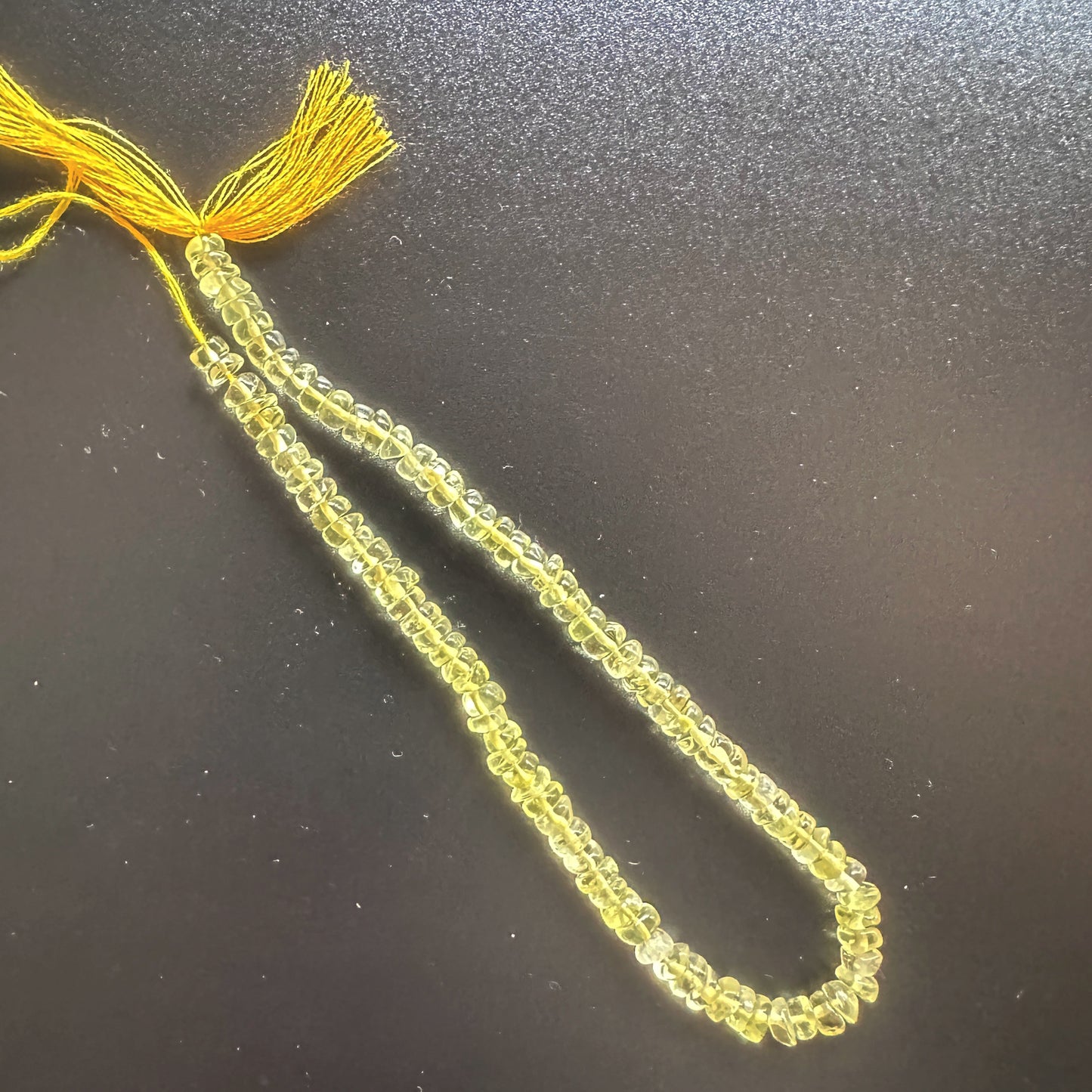 Close-up of Lemon Quartz beads arranged in a 21cm strand with glossy surface.
