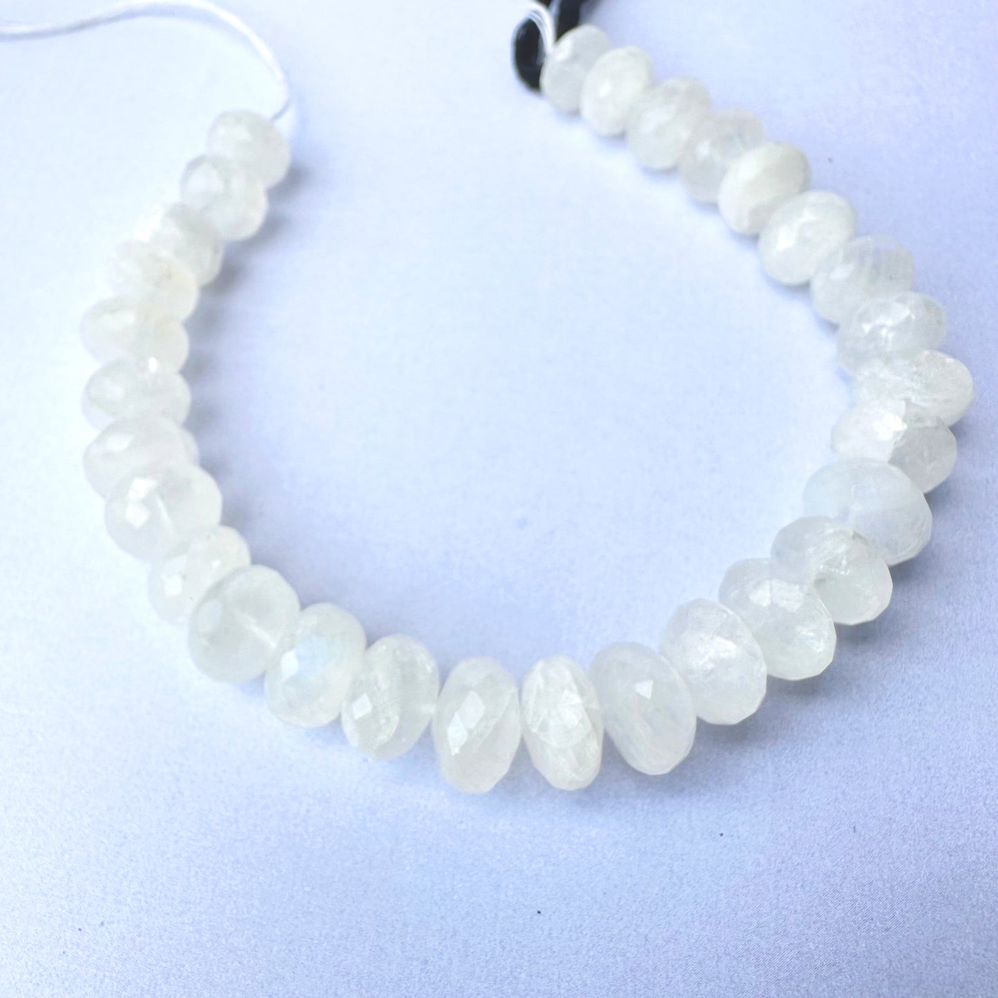 Close-up of moonstone beads showing soft glow and polished faceted surfaces.