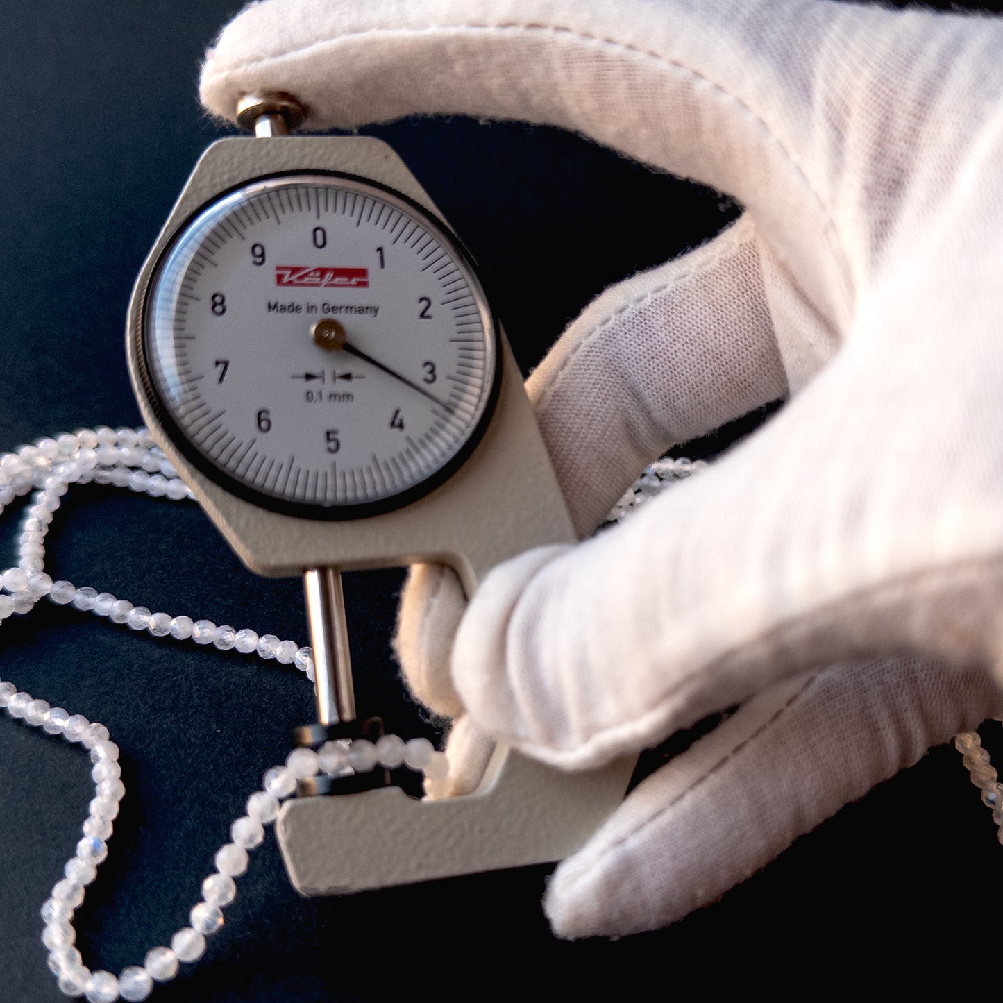 A dial gauge measures the Moonstone faceted rondelle 3.4mm gemstone.