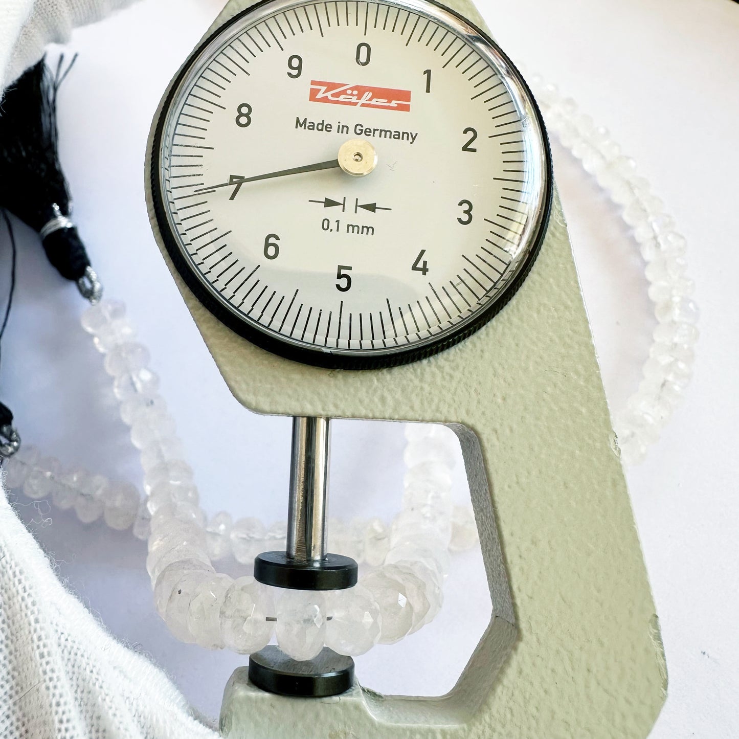 A dial gauge measures the Moonstone faceted rondelle 7–7.5mm gemstone