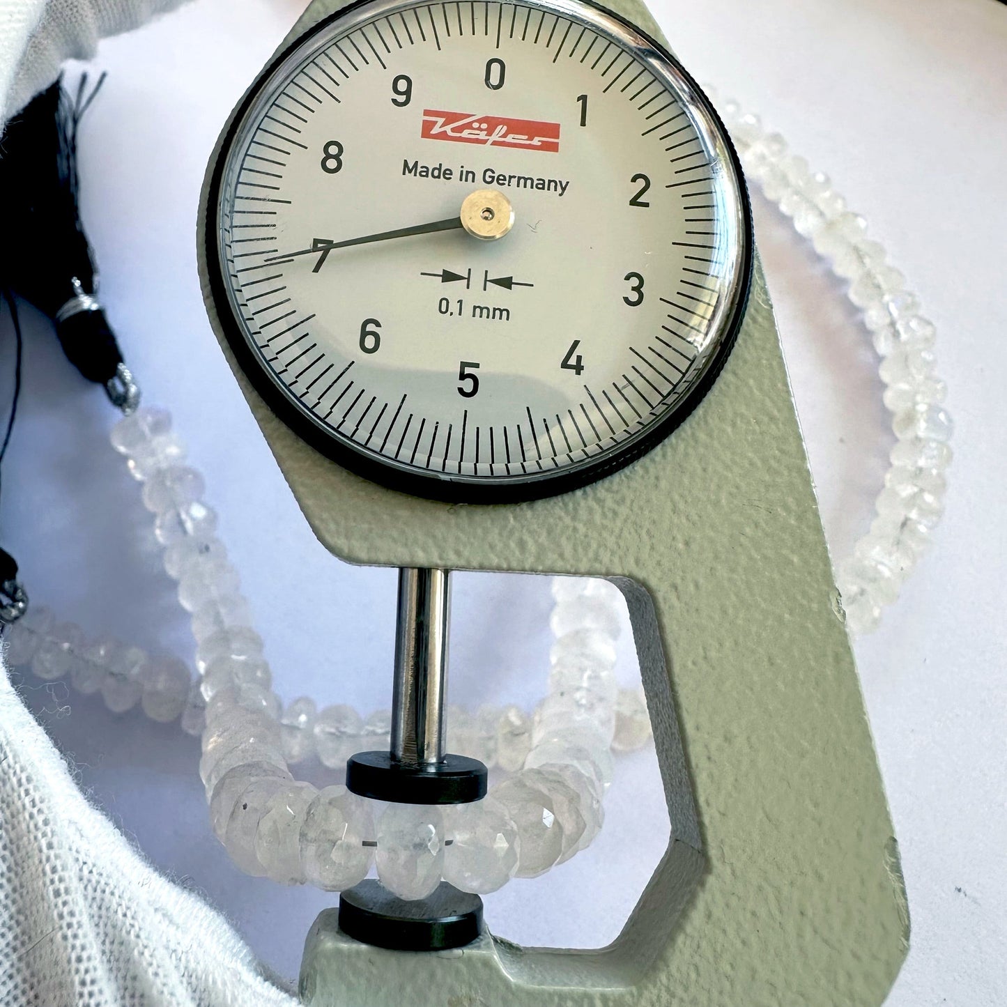 A dial gauge measures the Moonstone faceted rondelle 7.5mm gemstone.