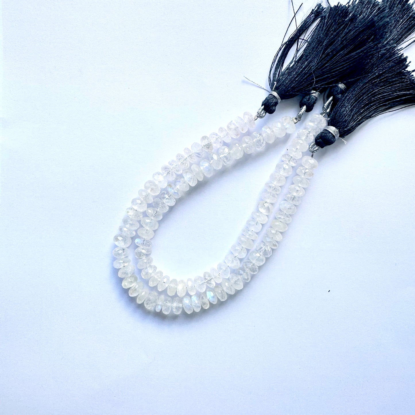 Gleaming moonstone rondelle gemstones arranged in a uniform pattern on thread.