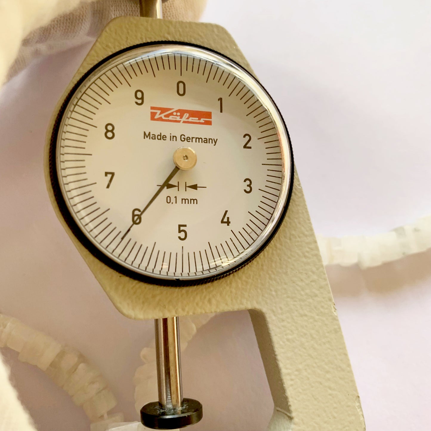A dial gauge measures the Moonstone heishi square 6–6.5mm gemstone.
