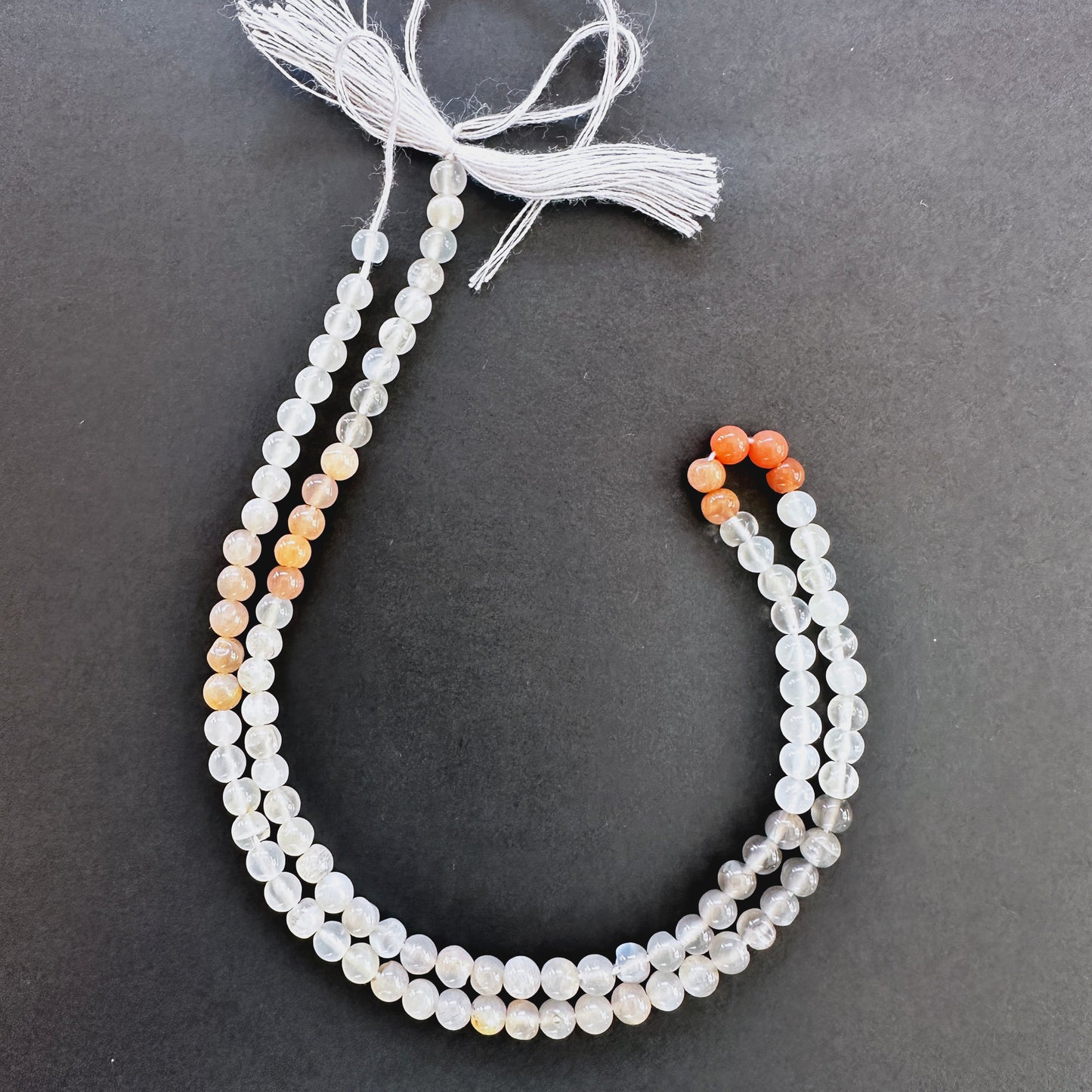 Close-up of Moonstone smooth round beads with soft white tones and blue flashes.
