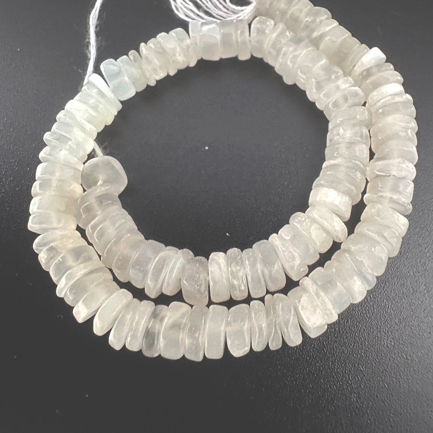 Close-up of Moonstone beads arranged in a 21cm strand with soft shimmer.