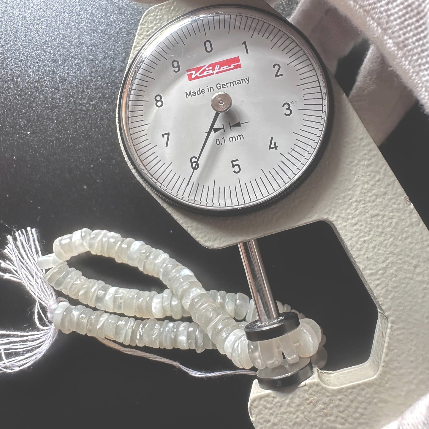 A dial gauge measures the Moonstone smooth wheel 6mm gemstone.