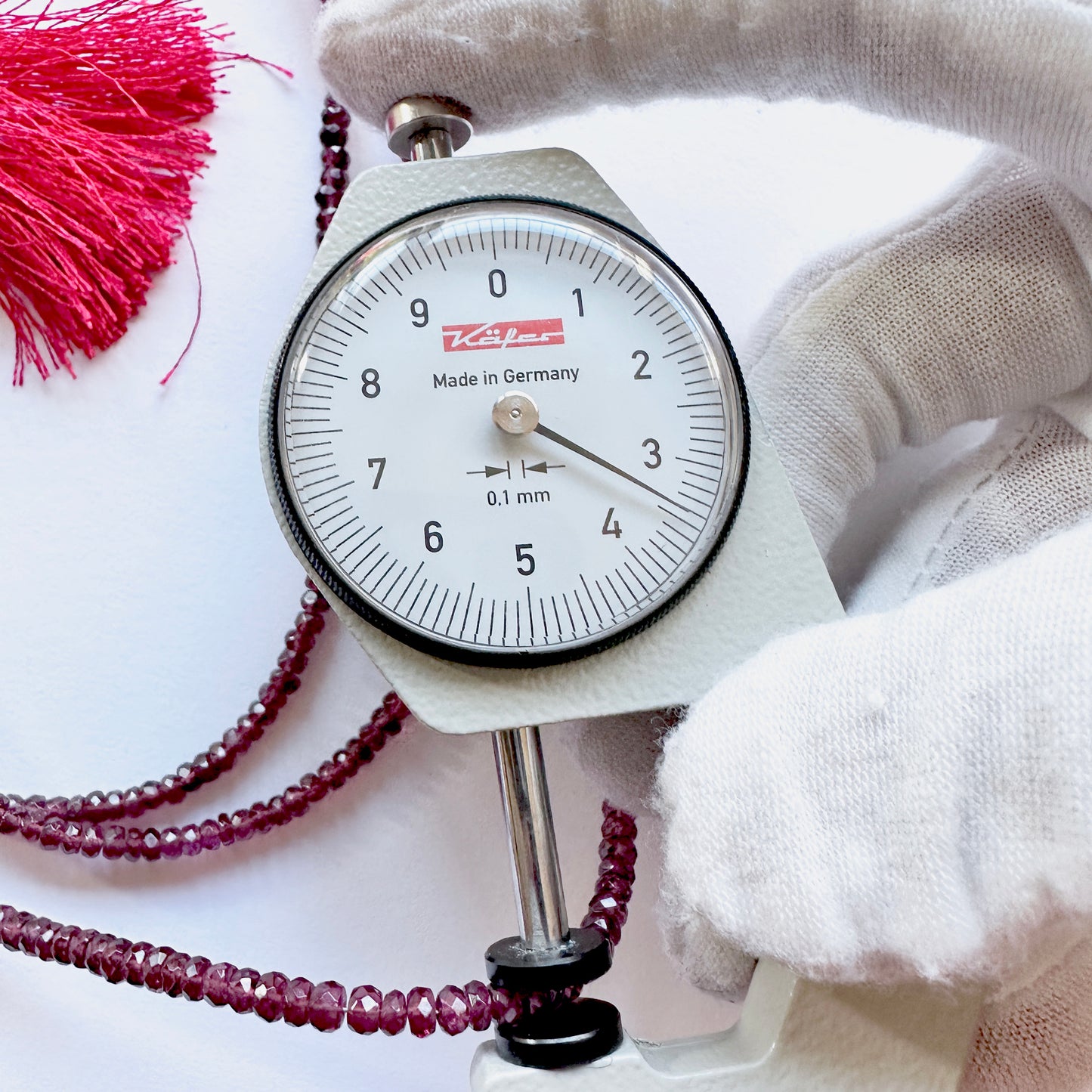 A dial gauge measures the Mozambique Garnet round cut gemstone.