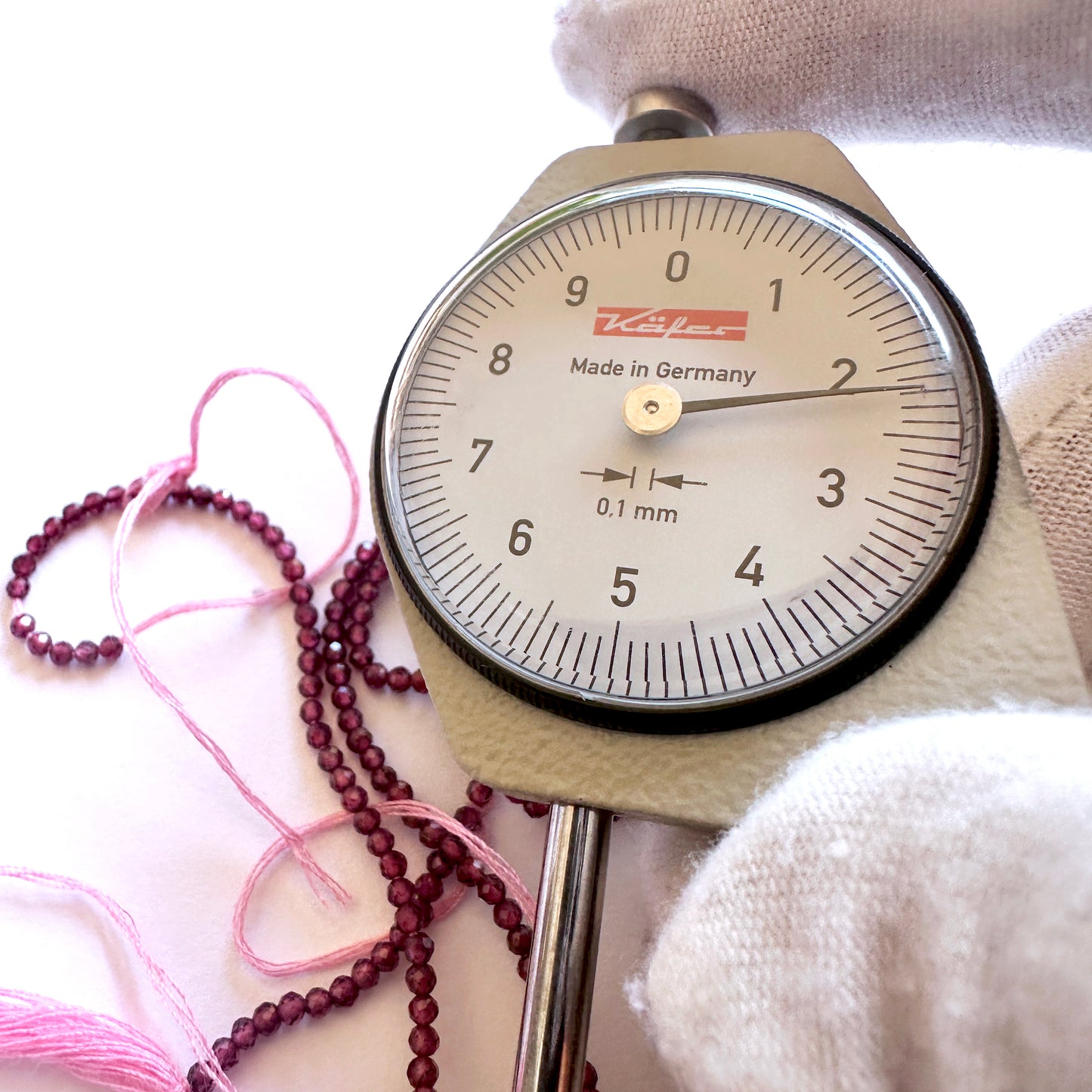 A dial gauge measures the Mozambique Garnet faceted rondelle 2.2mm gemstone.