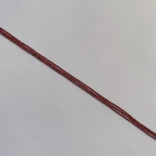 Strands of 2mm Garnet beads reflecting natural light, showing their brilliant cut and colour.