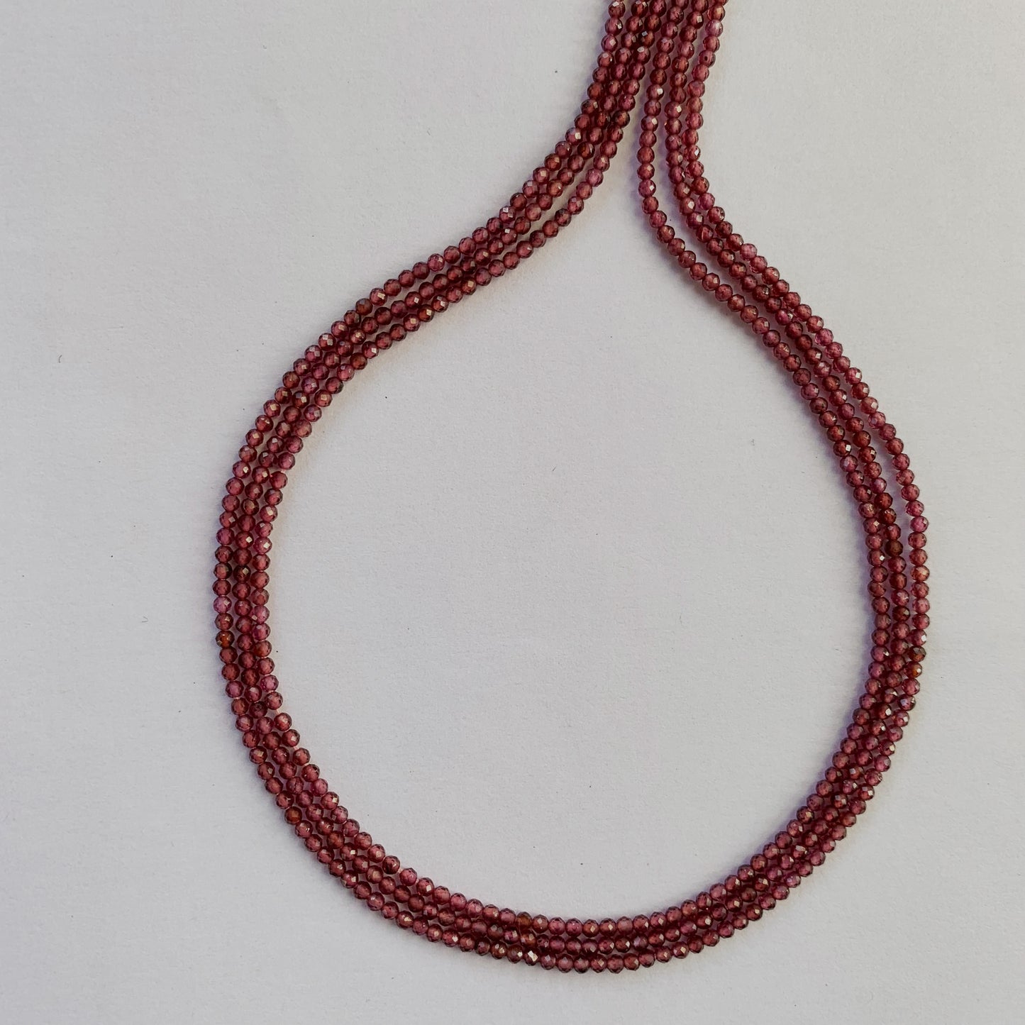 Detailed view of finely faceted Garnet rondelles aligned along a uniform 32cm strand.