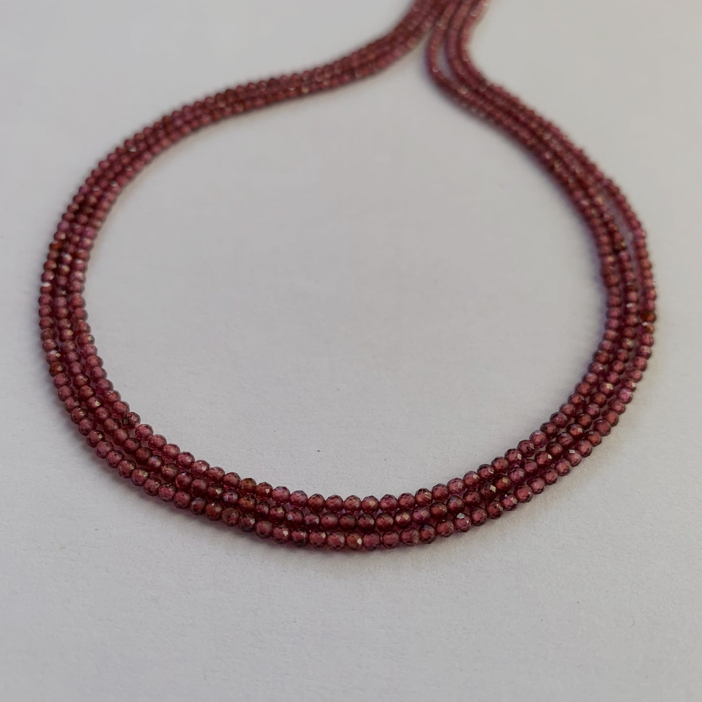 Close-up of deep red Mozambique Garnet gemstones with a precision faceted rondelle cut.