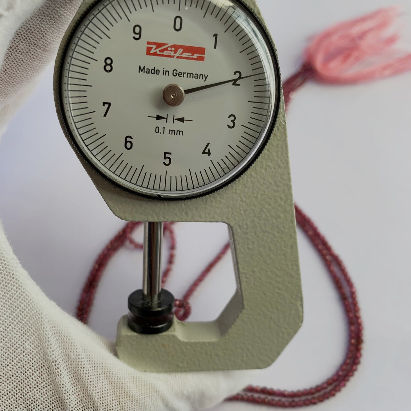 A dial gauge measures the Mozambique Garnet faceted rondelle 2mm gemstone.