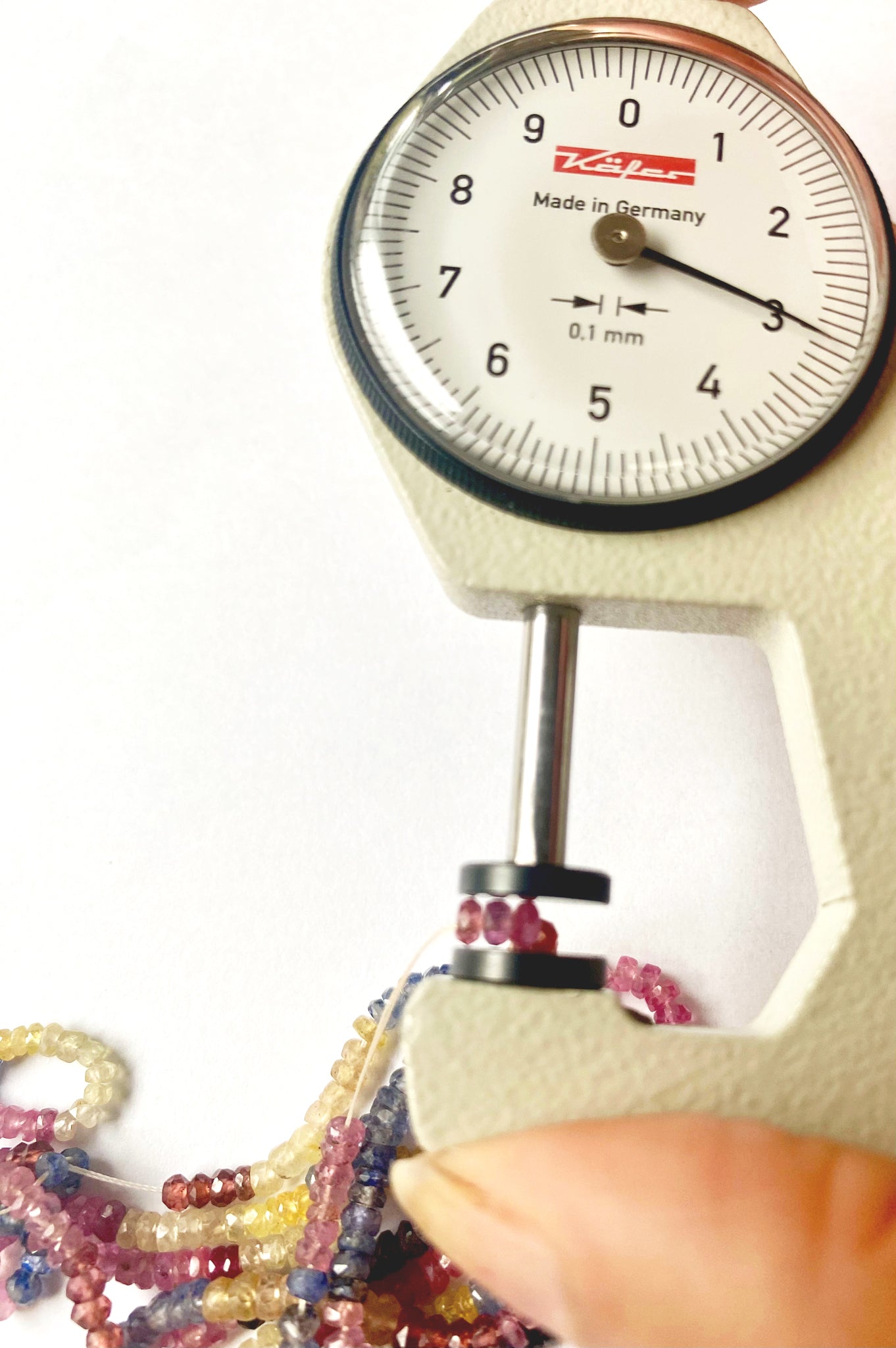 A dial gauge measures the Multi Precious faceted rondelle 2.8mm gemstone.
