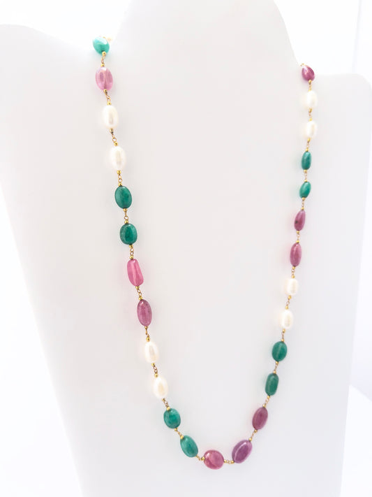 Multi precious strand necklace showcasing vibrant green emeralds, deep red rubies, and glowing pearls.