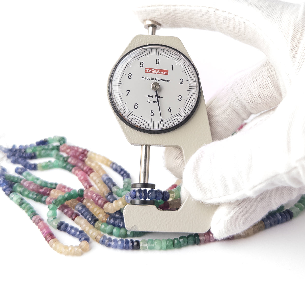 A dial gauge measures the Multi Precious Ruby Blue Sapphire Yellow Sapphire and Emerald Faceted Rondelle 3-3.6mm gemstone.
