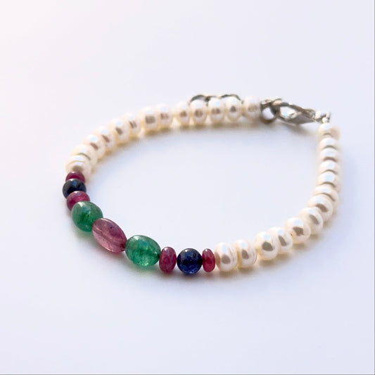 Close‑up of polished oval gemstone and pearl beads arranged on a finished bracelet.