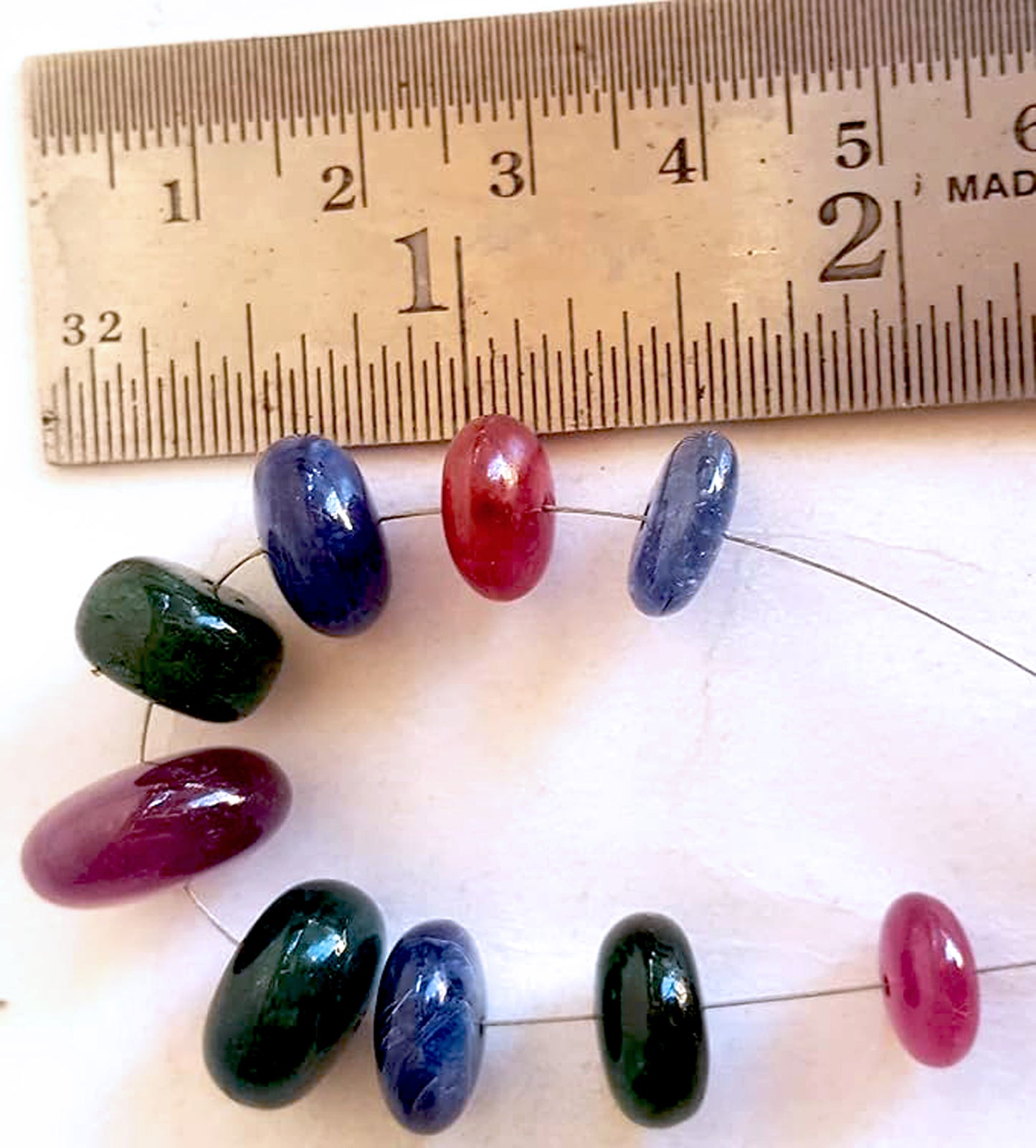 A ruler measures the ruby smooth rondelle 12mm gemstone for precision and quality assurance.
