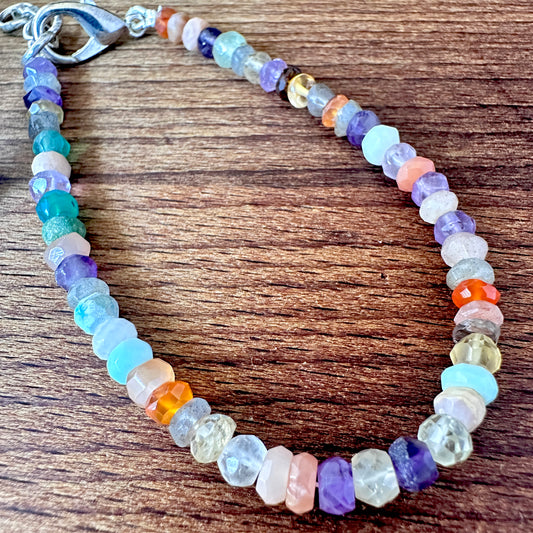 Close-up of multi gemstone bracelet featuring faceted rondelle stone beads, vibrant colours and polished shine.