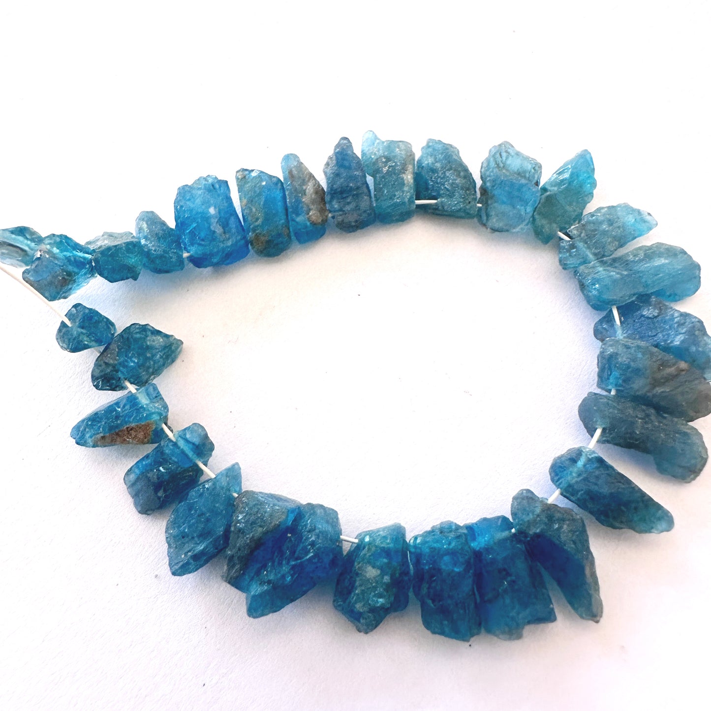 Neon Apatite rough stones with 0.5mm bead holes, ideal for secure stringing and bold jewellery.