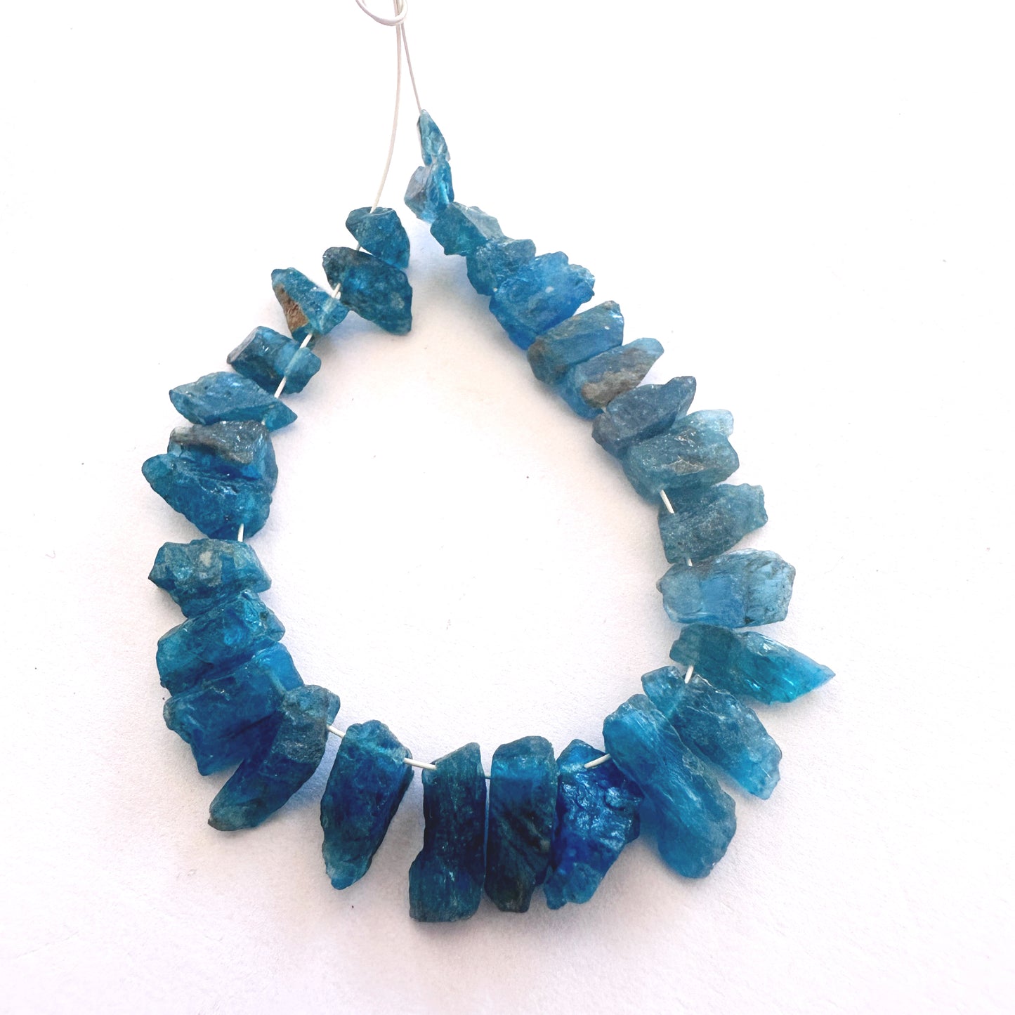 Neon Apatite rough beads with vivid blue colour and side-drilled 4–5mm size.