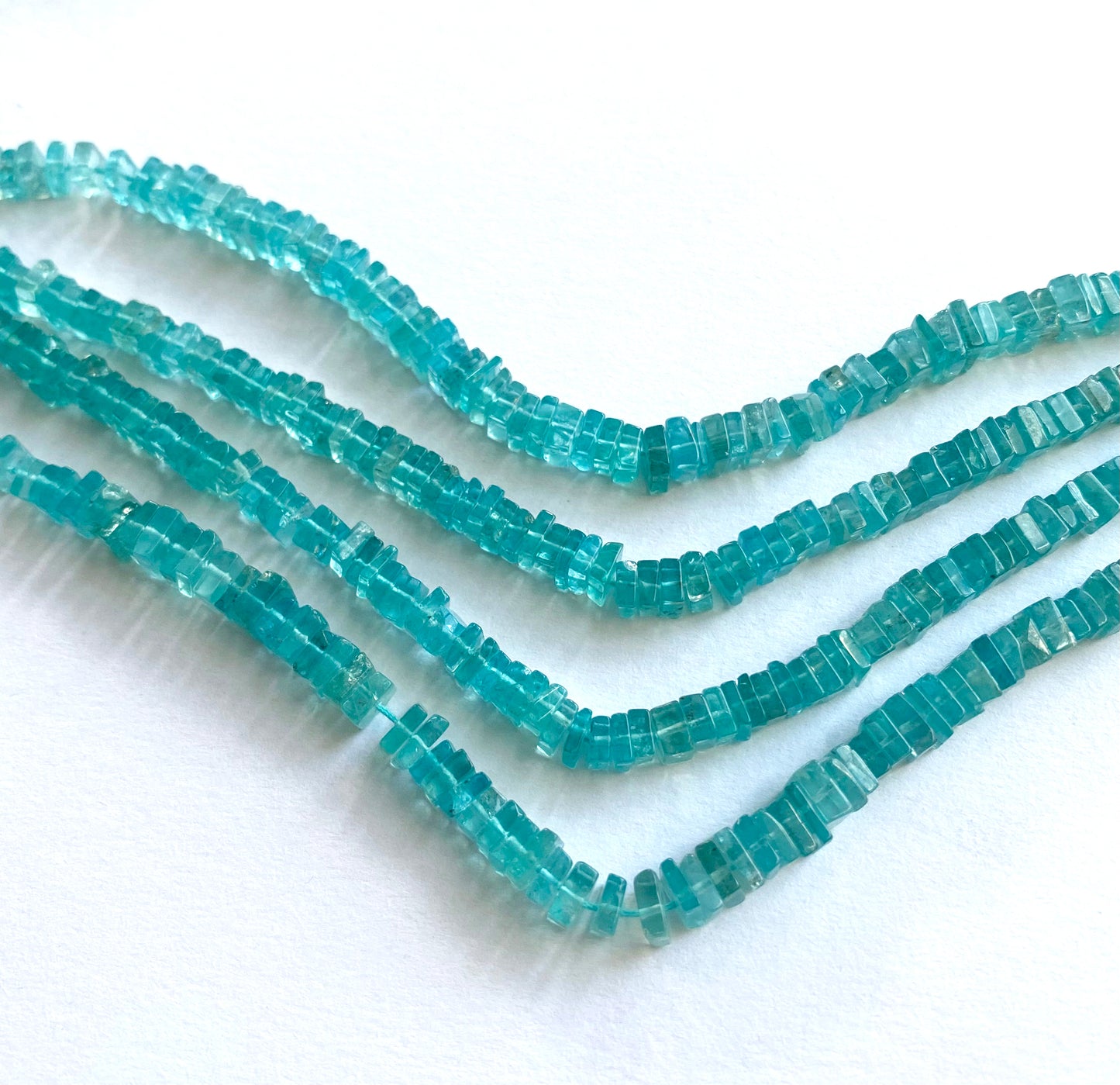 Flat-cut Neon Apatite heishi beads with a glossy surface and consistent square shape.