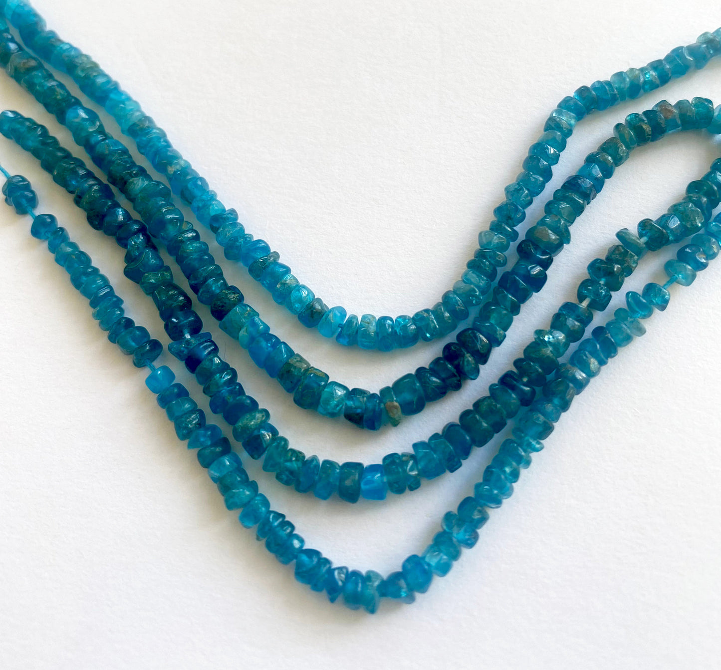 Strands of neon apatite beads in 3.5–4mm and 4.0–4.2mm sizes, highlighting their smooth finish