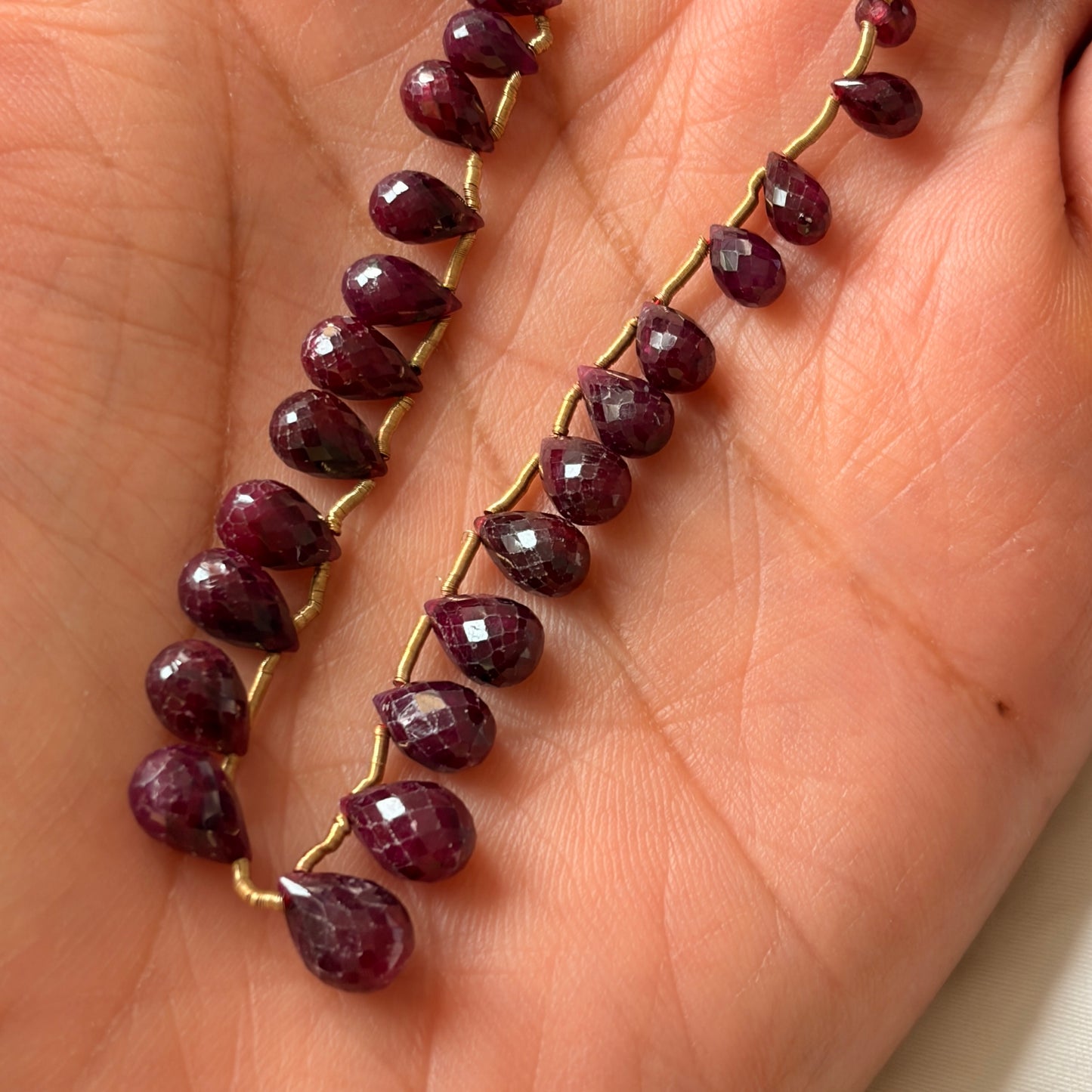 Ruby strand with deep red colour in a person's hand.