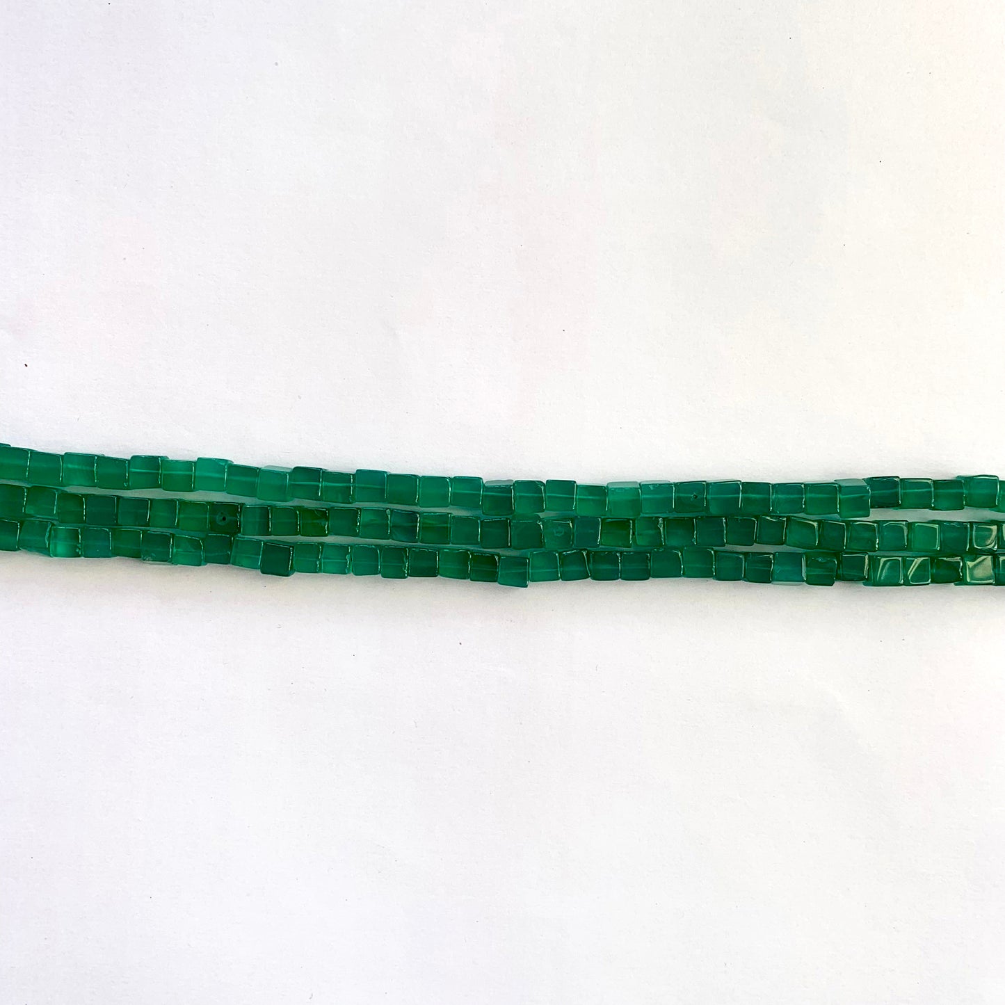 Detailed view of green Onyx cube beads with sharp edges and a radiant shine on each facet.