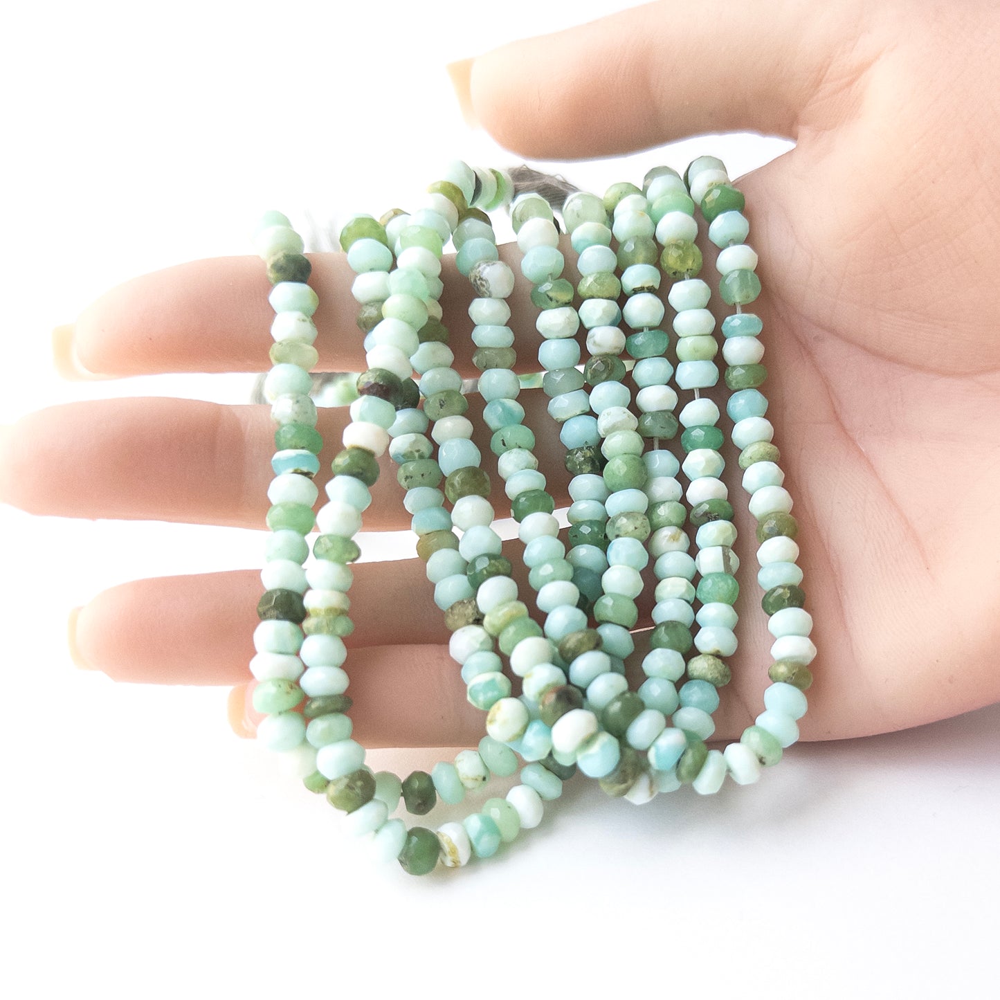 A person holds delicate strands of Mint Green Opal beads, showcasing their faceted rondelle design.
