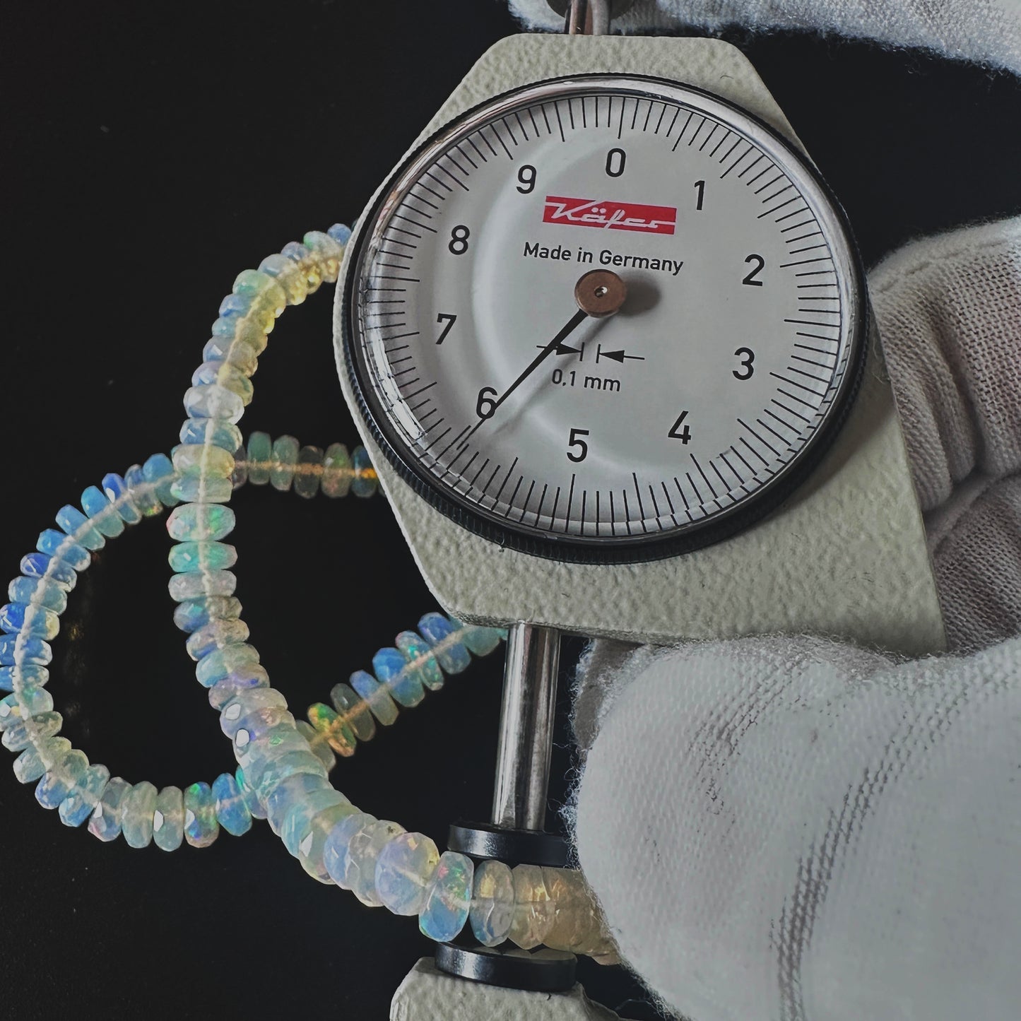 A dial gauge measures the Opal faceted rondelle 5.5-7.0mm gemstone.