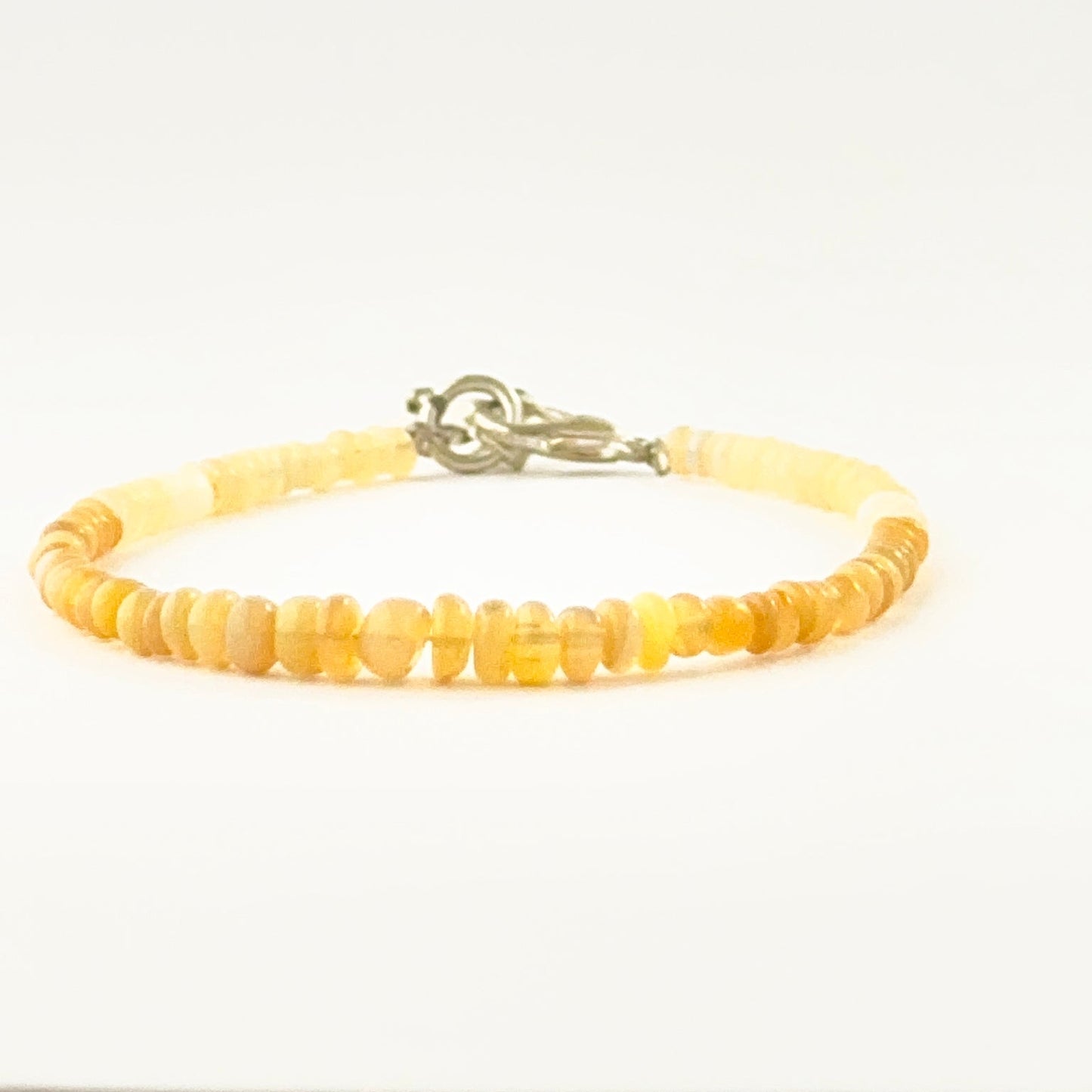 Single‑strand opal bracelet featuring smooth rondelle beads and adjustable closure.