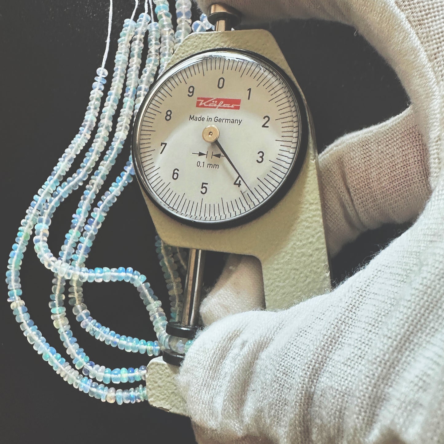 A dial gauge measures the Opal smooth rondelle 3.2-4.0mm gemstone.