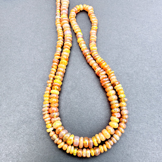 Close up of Opal with orange and yellow beads on a gray background.